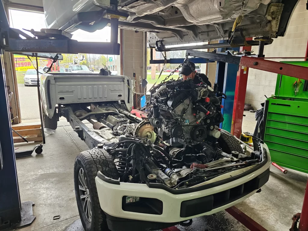 Truck with cab lifted, exposing engine and chassis during repair in an auto shop.