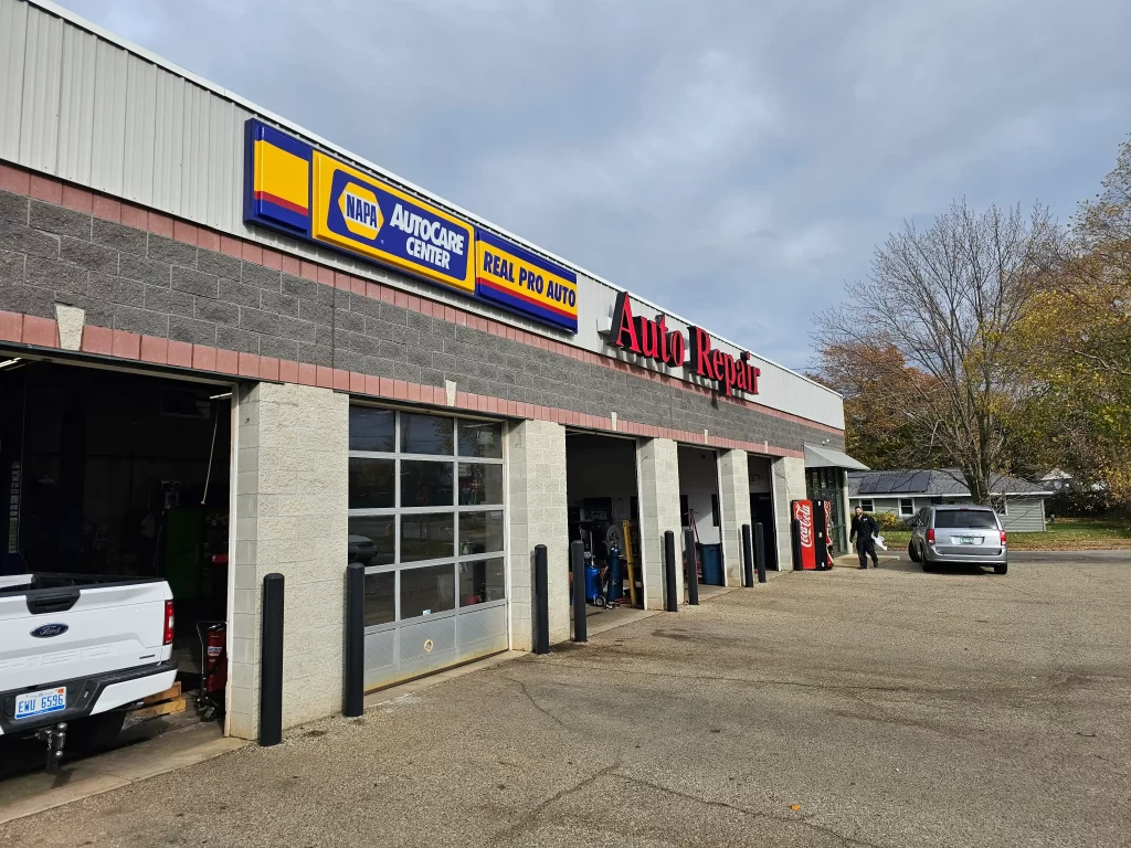 Exterior of Real Pro Auto with NAPA AutoCare signage, open garage bays, and a parking area.