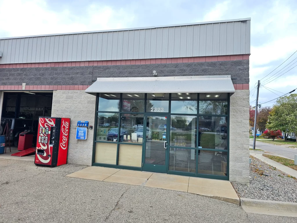 Real Pro Auto storefront with glass doors, a Coca-Cola vending machine, and a key drop box outside.