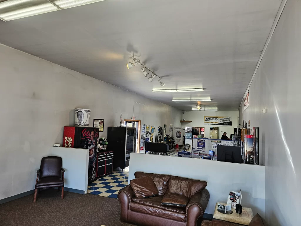 Real Pro Auto waiting area with chairs, a leather couch, and a vending machine, leading to the service desk.