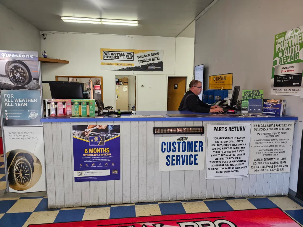 Real Pro Auto customer service desk with promotional materials, signs, and a staff member assisting customers.