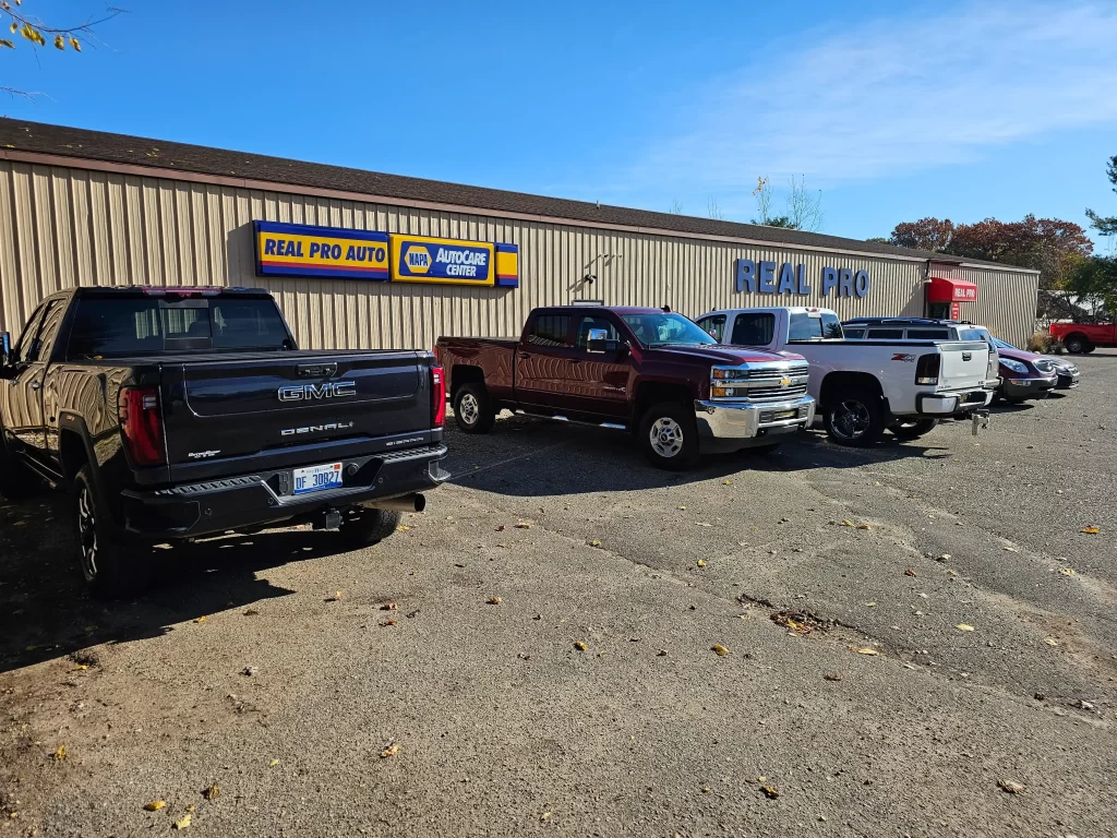 Pickup trucks parked outside Real Pro Auto, a Napa AutoCare Center, on a sunny day.