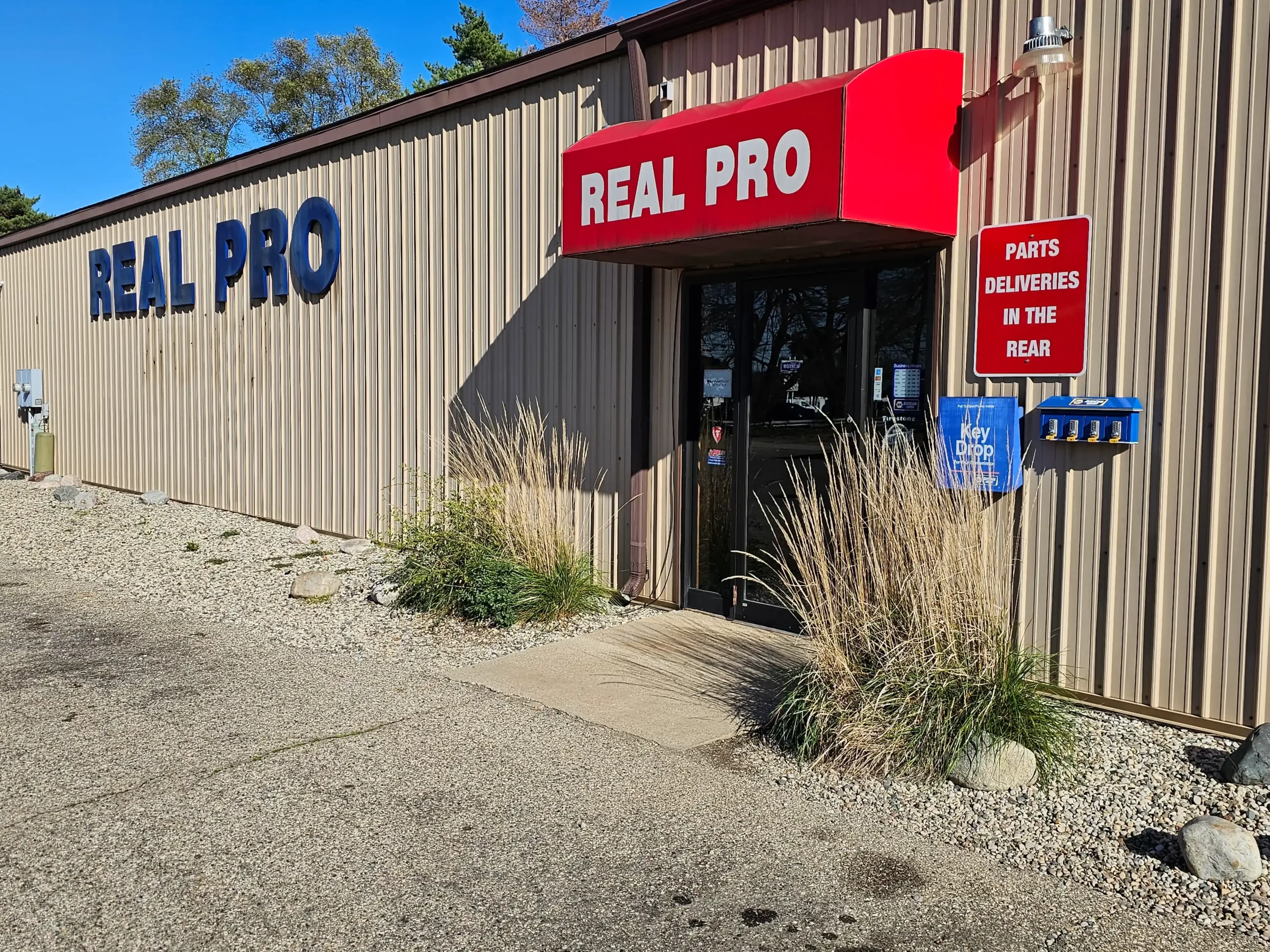 Real Pro Auto building with red awning, "Parts Deliveries in the Rear" sign, and key drop box.