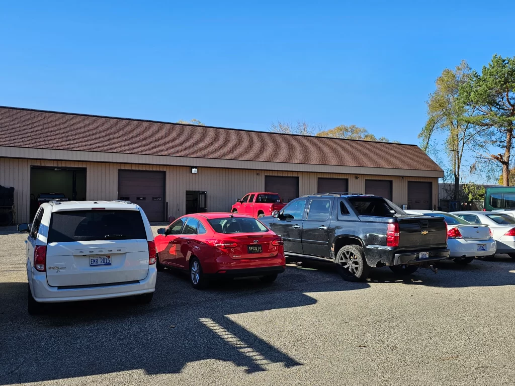 Real Pro Auto building entrance with a red awning, signage, and plants by the doorway.