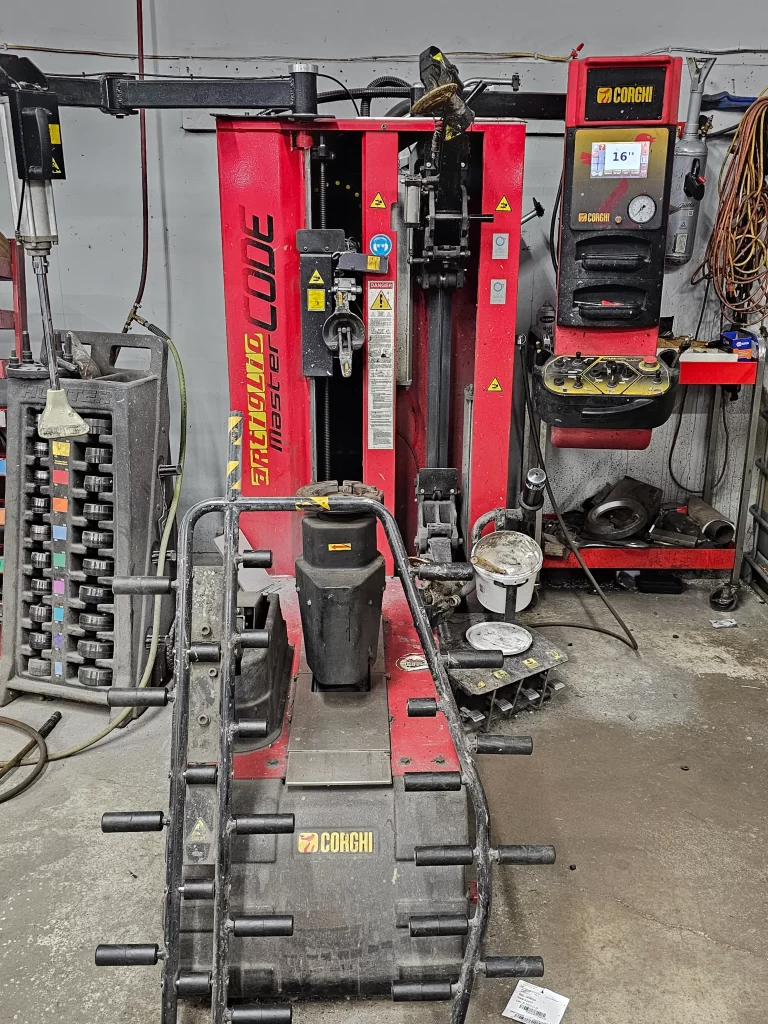 Red Corghi tire-changing and balancing equipment in an auto repair shop.