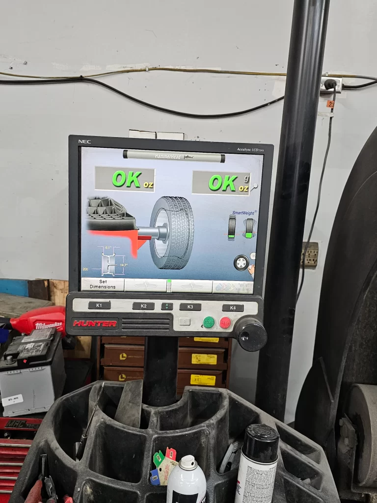 Hunter wheel balancer screen showing "OK" status for tire weight and balance in a repair shop.