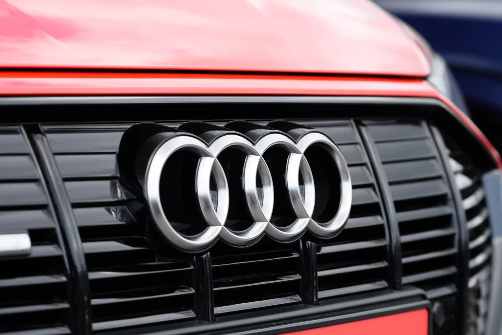 Close-up of an Audi grille with the iconic four-ring logo on a red car.