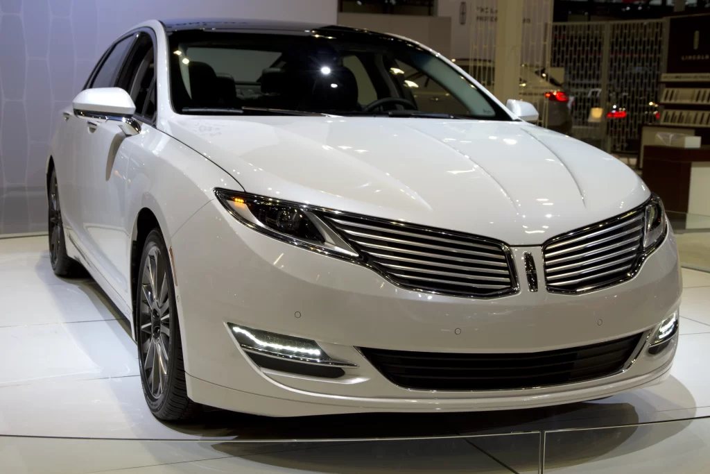 A sleek white Lincoln sedan displayed indoors, showcasing its front grille and modern design.