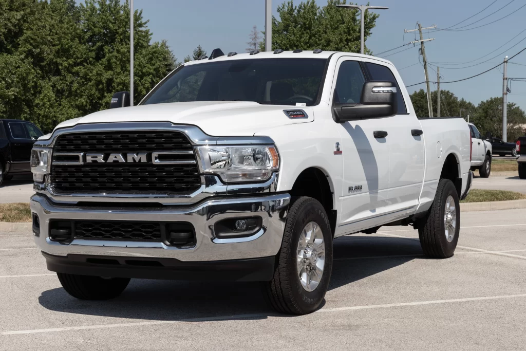 A white RAM pickup truck parked in a lot, showcasing a bold front grille and chrome accents.